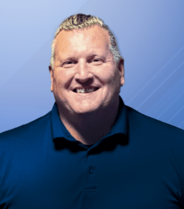 A man with grey hair in a navy polo poses for a headshot. He is the father of a deaf child.
