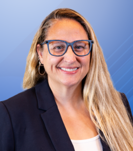 A woman wearing blue glasses with long blonde hair smiles for a headshot. She is a project manager for the Clerc Center.