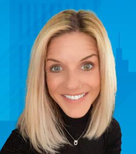 Holly is a white cis woman with light skin, blue eyes, straight blonde hair, pictured smiling wearing black shirt, on gray sofa with green pillow and light blue wall.