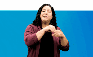 Sarah Honigfeld, Director, Early Intervention and Regional Early Acquisition of Language (REAL), dressed in a maroon blazer and a black top signs into camera about the REAL early language acquisition project.
